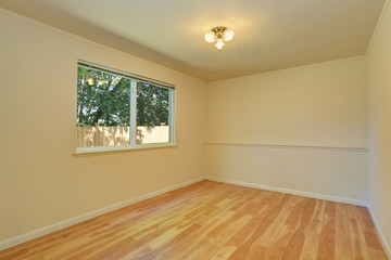Empty room in warm peach colors with hardwood floor.