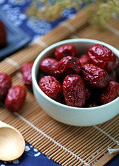 A bowl of red dates on spread a blue cloth on the desktop