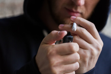 close up of addict lighting up marijuana joint
