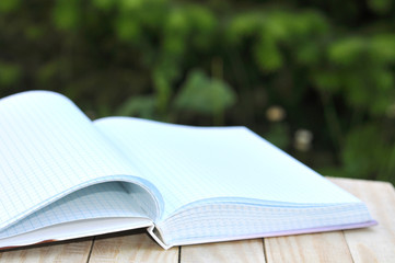 Open book on wooden table on natural background