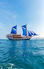 Fototapeta na wymiar Vintage Wooden Ship with Blue Sails