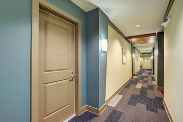 Long blue corridor with carpet floor in apartment building