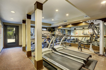 Gym room for residents in apartment building. Different exercise equipments and weights