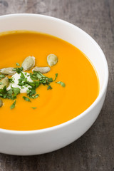 Pumpkin soup and pumpkin seeds on rustic wooden background

