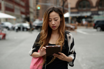 Young Asian woman in city using tablet computer
