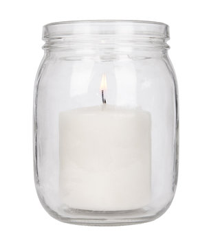 A Lit Pillar Candle In A Glass Jar Isolated On A White Background