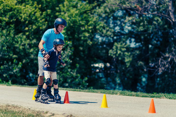 Senior man, teacher of roller skating with little boy
