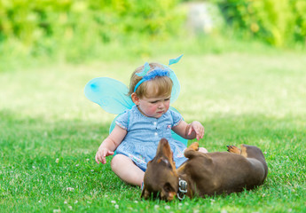 The beautiful fairy girl plays with a dog on grass