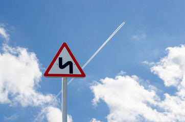 Road sign on sky background. The trace of the plane