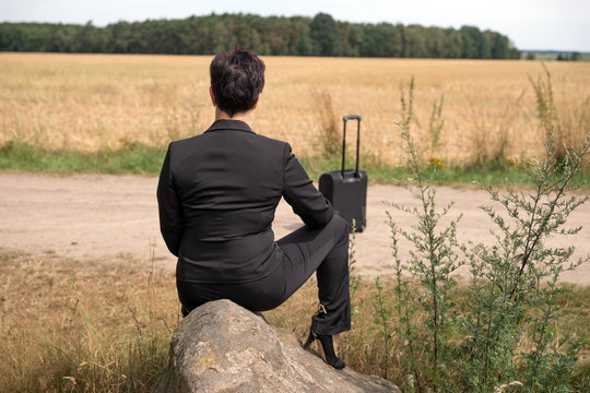 Businesswoman waiting with suitcase for a business trip