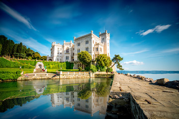 View on Miramare castle on the gulf of Trieste on northeastern Italy. Long exposure image technic with reflection on the water - obrazy, fototapety, plakaty