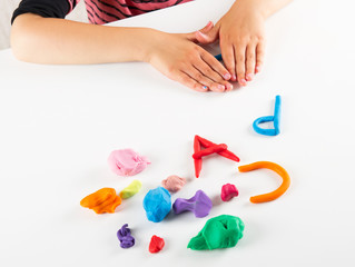 Child hands with colorful clay. Mold letters