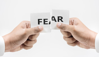 Hand tearing paper with FEAR word in white tone background.