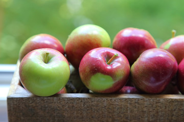 fresh red apples in wooden box on a green background