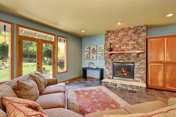 Cozy living room with blue walls and stone tile fireplace.