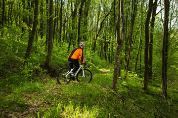 Naklejka premium Biker in orange jersey on the forest road