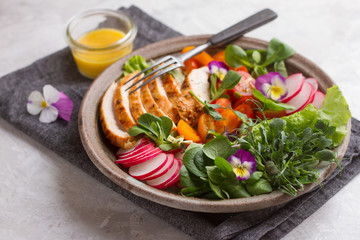 Spring salad with vegetables, chicken breast and edible flowe