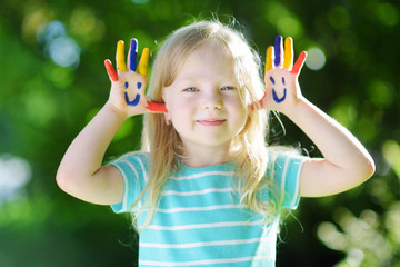 Adorable little girl with her hands painted having fun outdoors © MNStudio