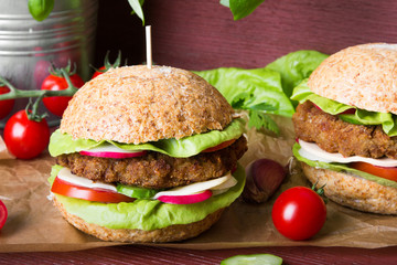 Homemade hamburgers with fresh vegetables on wooden background