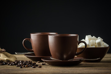 coffee cups, beans and sugar on rustic wooden table background

