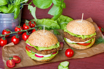 Homemade hamburgers with fresh vegetables on wooden background