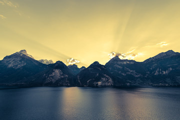 Fototapeta na wymiar Mountainous landscape. Evening in the Alps. Rays of of the setting sun over the mountain peaks. Lake Uri. 