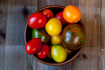 Big plate with red tomatoes on a wooden table, top view, copy space