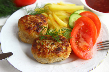 Fried cutlets with potatoes on a white plate.