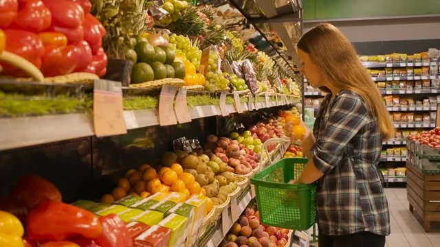 Beautiful young woman shopping for fruits products at a supermarket