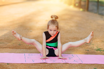 Girl performs gymnastic exercise in the fresh air