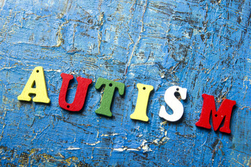 Colourful letters spelling out Autism on abstract blue background.