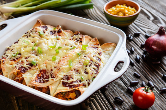 Traditional Mexican enchiladas with chicken meat, spicy tomato sauce, corn, beans and cheese