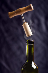 Opening a wine bottle with a corkscrew on a black background. Wine bottle with steam. Levitation of...