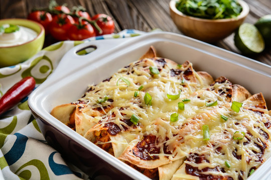 Traditional Mexican enchiladas with chicken meat, spicy tomato sauce, corn, beans and cheese