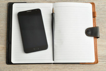 An open notebook displayed with a smart phone and a fountain pen