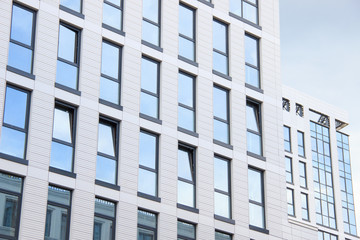 A high-rise office building. Some windows opened. Blue sky reflection