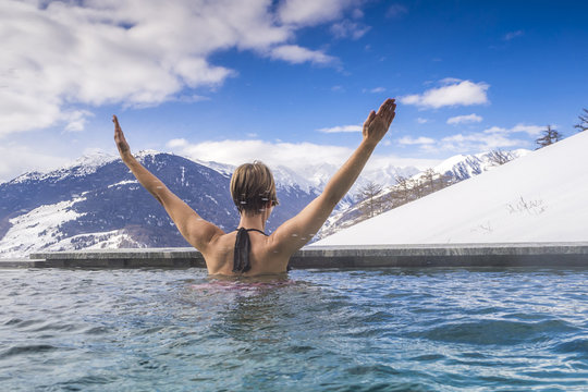 Frau geniesst Bergpanorama im Winter vom Pool aus