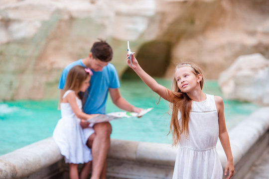 Family with touristic map near Fontana di Trevi, Rome, Italy. Little girl with toy airplane background of Trevi Fountain. Happy father and kids enjoy italian vacation holiday in Europe.