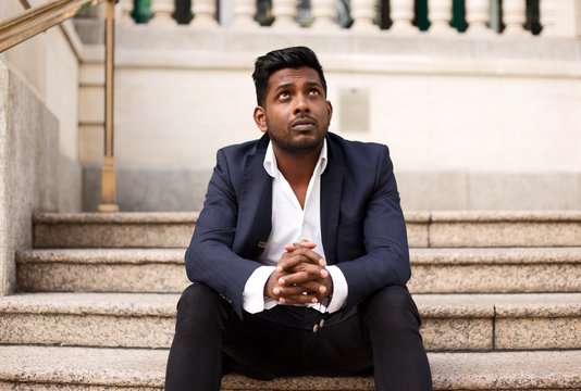 Young Indian Business Man Sitting On A Step Thinking