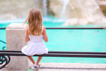 Adorable little girl looking to the Fountain of Trevi in Rome. Happy kid enjoy her european vacation in Italy