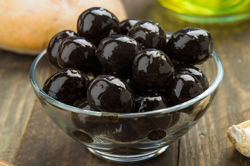 glass bowl with black olives on rustic wood