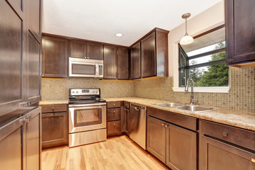 Fototapeta premium Wnętrze kuchni z brązowymi szafkami i granitowymi blatami.