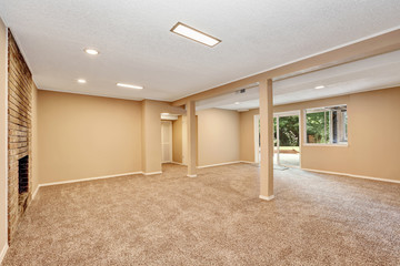Empty spacious room with brick fireplace and carpet floor