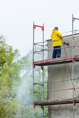 Man cleaning wall. Scaffolding
