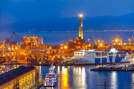 Historical Lanterna old Lighthouse, container and passenger terminals in seaport of Genoa on Mediterranean Sea, at night, Italy.