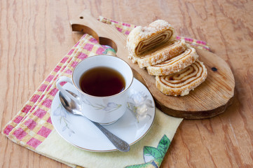A cup of tea and a roll is on the cutting board