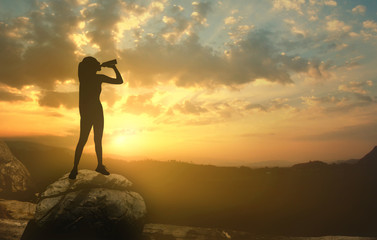 Silhouette of a girl at sunset with a bottle of water