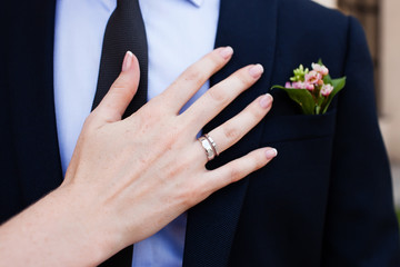 Wedding boutonniere and the hand of bride with ring