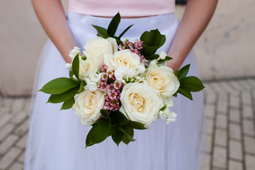 Beautiful wedding bouquet of roses in the hands of the bride