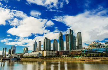 Photo of skyscrapers in Puerto Madero business district in Buenos Aires against colorful blue sky with clouds on a sunny day